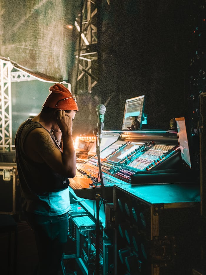 A man in a beanie standing in front of a mixing desk